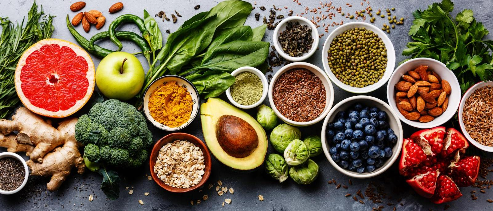 Colorful variety of plant-based foods including fruits, vegetables, nuts, seeds, and grains