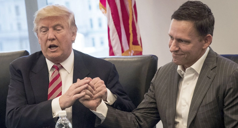 Donald Trump with Peter Thiel, co-founder of Palantir, clasping hands during a meeting with an American flag in the background